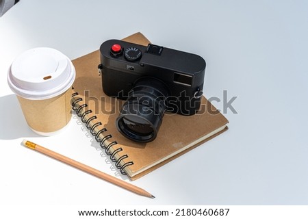 Hot coffee latte with latte in cup made of paper and camera in notebook on white wood table desk on top view. As breakfast In a coffee shop at the cafe,during business work concept