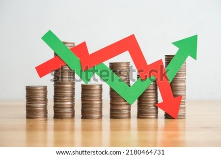 Stack coins and arrow red green graph chart volatility up and down on wooden table background. Business, financial and investment concept. Risk, fluctuation in stock market and bitcoin cryptocurrency.