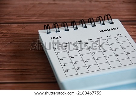 January 2023 white desk calendar on wooden table background.