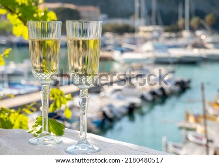 Lunch with two glasses of French champagne sparkling wine and view on colorful fisherman's boats in old harbour in Cassis, Provence, France