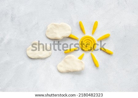 Weather forecast concept with plasticine sun and clouds, top view