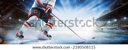 Close up of ice hockey stick on ice rink in position to hit hockey puck.