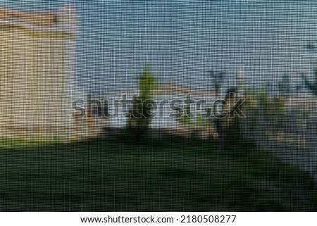 View through mosquito wire mesh or net or screen with a blurred countryside background. Selective focus. Rusty fly mesh texture images. 