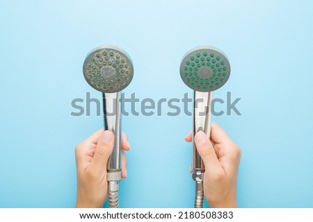 Young adult woman hands holding new and old shower heads on light blue table background. Pastel color. Compare two objects with and without limescale. Dirty and clean. Closeup. Point of view shot. Royalty-Free Stock Photo #2180508383