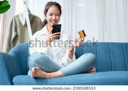 Young beauty Asian woman shopping payment online with credit card on smartphone on sofa in living room at home. Royalty-Free Stock Photo #2180508553