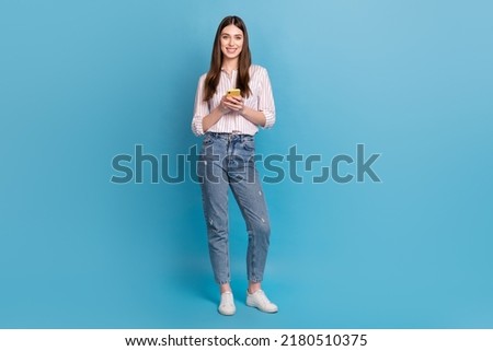 Full length body size view of attractive cheerful trendy girl using device gadget isolated over bright blue color background