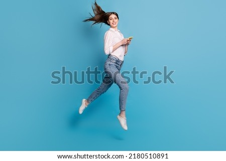 Full length body size view of attractive girl using gadget jumping fast speed isolated over bright blue color background