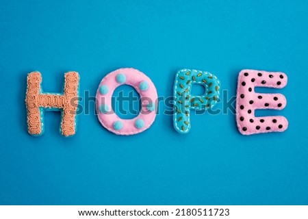 Stuffed felt letters with decorations. Word "Hope"  on isolated neutral background.  Handmade crafts. Flat lay.