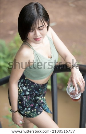 A woman model short hair in fashion suit take a photo on outdoor and studio and natural light, and she like a americano ice coffee