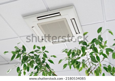 Cassette Air Conditioner on ceiling in modern light office or apartment with green ficus plant leaves. Indoor air quality and clean filters concept Royalty-Free Stock Photo #2180534085