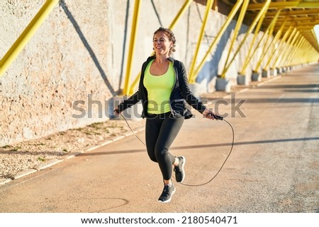 Middle age hispanic woman working out jumping rope at promenade Royalty-Free Stock Photo #2180540471