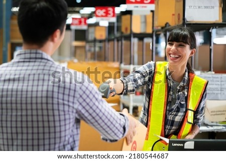 A young woman warehouse worker checking goods in a warehouse by scanning a barcode.