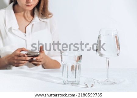 Casual style young woman texting on a smartphone. water glasses. Female model