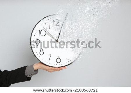 Time is running out. Woman holding vanishing clock against light grey background, closeup Royalty-Free Stock Photo #2180568721