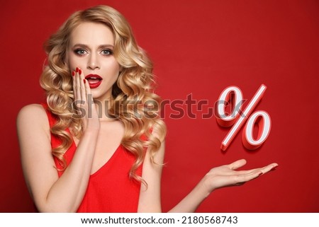 Surprised woman pointing at sign Percent on red background. Special promotion