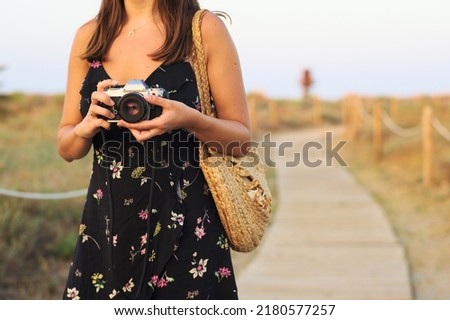 Young woman walking with an analog camera on the beach