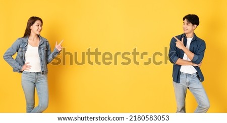 Two Young good looking asian couple using isolated on yellow background presenting to copy space Royalty-Free Stock Photo #2180583053