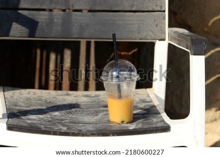 An unfinished glass with a soft drink is thrown on the street.