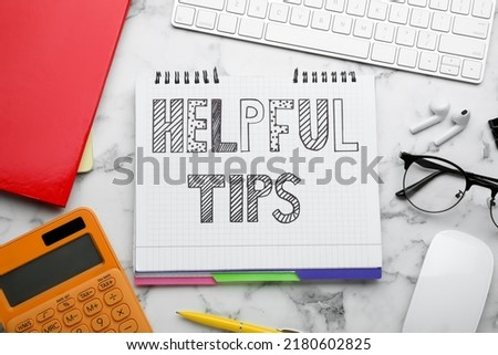 Flat lay composition with text Helpful Tips in notebook on white marble table