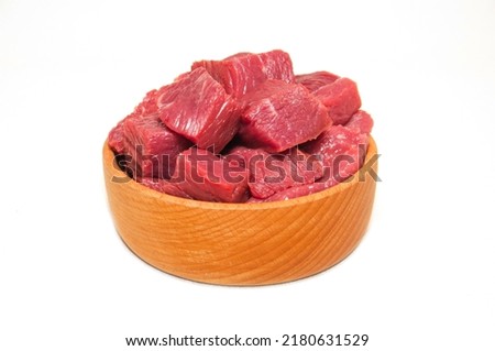 Square pieces of red beef meet in wooden bowl isolated