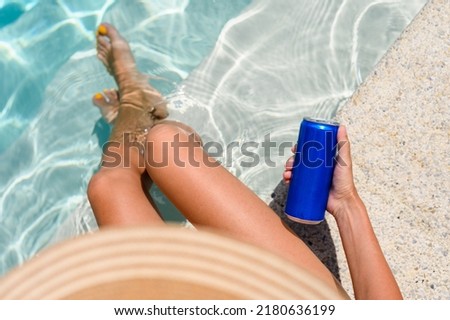 Girl by the pool with a can of cold drink on a summer day. Top view, selective focus on a can of drink. Royalty-Free Stock Photo #2180636199