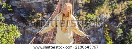 BANNER, LONG FORMAT Woman tourist on Old rusty bridge. Attraction Long extreme suspension iron bridge across the river Moraca. Sights of Montenegro. Landmark Montenegro