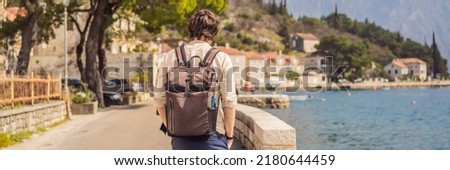 BANNER, LONG FORMAT Man tourist enjoying Colorful street in Old town of Perast on a sunny day, Montenegro. Travel to Montenegro concept. Scenic panorama view of the historic town of Perast at famous