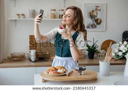 Beautiful girl takes a selfie with a cake in the kitchen