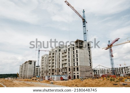 unfinished apartment buildings at the construction site and cranes in background. High quality photo