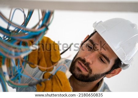 Electrician mounting wiring for electric sockets on the construction site of a new house,Construction concept. Royalty-Free Stock Photo #2180650835