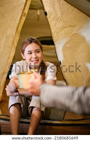 Portrait, Happy young Asian friends camping and relaxing together, enjoy talking and having a hot warm drink together at night. Teens camping concept.