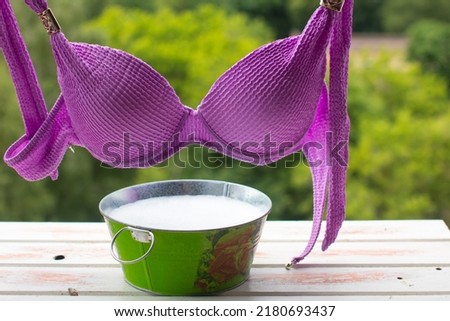 a woman's swimsuit dries on a rope. Metal basin with soapy water