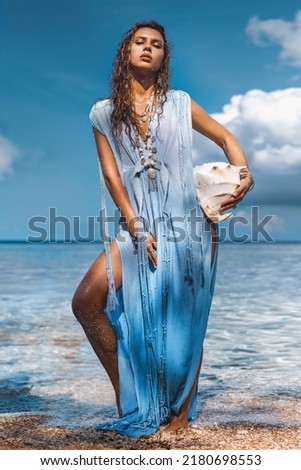 beautiful young stylish woman on in water with sea shell
