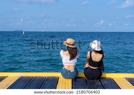 Two women friends or couple relaxing and watching views together on tropical beach travel summer holidays. Female tourists enjoy traveling to exotic nature in their leisure time. Friendship concept