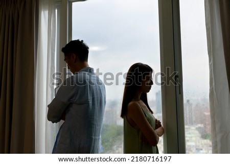 silhoutte of asian couple has a serious argue in front of the window at home - they turn around face another side against each other Royalty-Free Stock Photo #2180716197