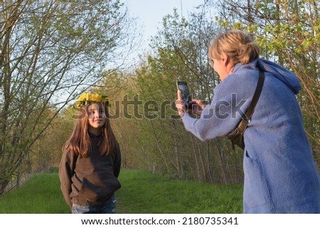 Family photography at sunset in the forest. Mom takes a picture of her daughter on a smartphone in nature