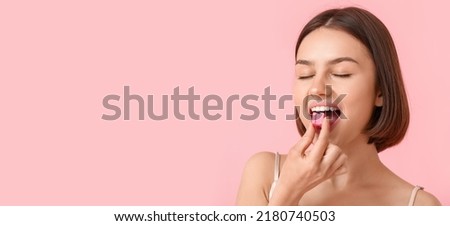 Young woman with chewing gum on pink background with space for text Royalty-Free Stock Photo #2180740503