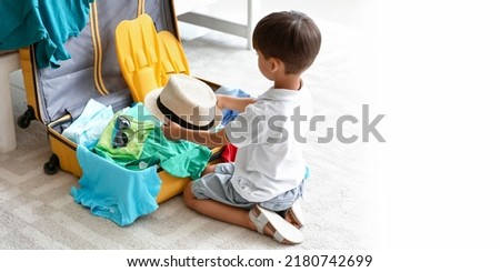 Little boy packing suitcase at home. Banner for design Royalty-Free Stock Photo #2180742699