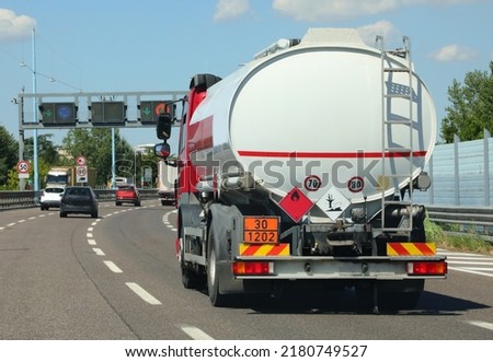 tanker truck for the transport of flammable material runs fast on the highway with vehicular traffic Royalty-Free Stock Photo #2180749527