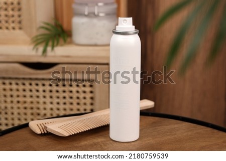 Dry shampoo spray and combs on wooden table in bathroom