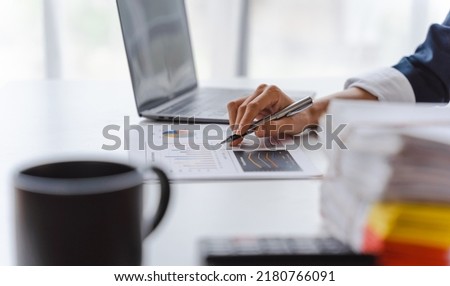 Young Asian business woman using laptop computer at working desk, felling happy, doing planning analyzing the financial report and tax charts.