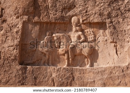 King on his horse carved into sandstone rock wall at Necropolis. King burial site of ancient Persia. 