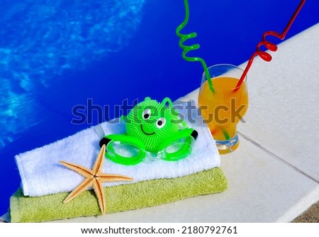 Goggles for swimming, a drink, straws for drinking, a starfish and a towel on the background of the pool concept of relaxation. Summer family vacation concept
