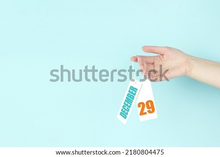 December 29th. Day 29 of month, Calendar date. Hand hold price tag with calendar date on blue background.  Winter month, day of the year concept
