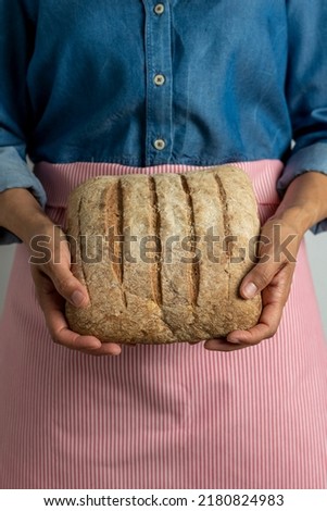 Young woman holding freshly homemade rustic bread - stock photo