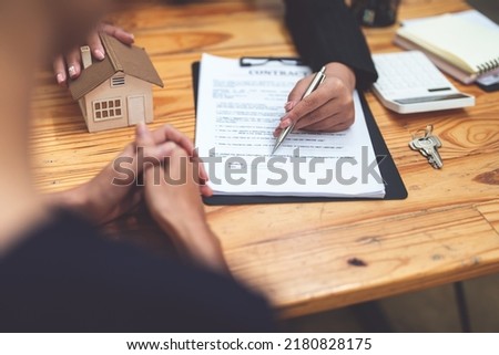 Asian female bank employee asking a customer to read the contract before signing to agree to buy a house, real estate concepts