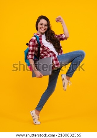 Back to school. Teenager schoolgirl hold notebook laptop. School children on isolated yellow studio background. Run and jump, jumping kid. Royalty-Free Stock Photo #2180832565