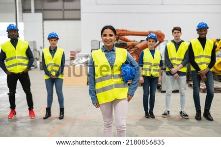 group of male and female engineers in a factory, Hispanic woman in front