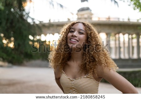 pretty hispanic woman with curly hair smiling traveler in the city Royalty-Free Stock Photo #2180858245
