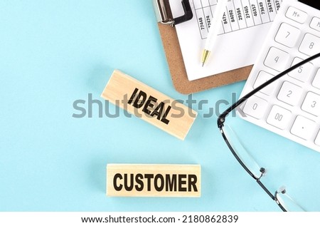 IDEAL CUSTOMER text written on a wooden block with clipboard,eye glasses and calculator Business concept.